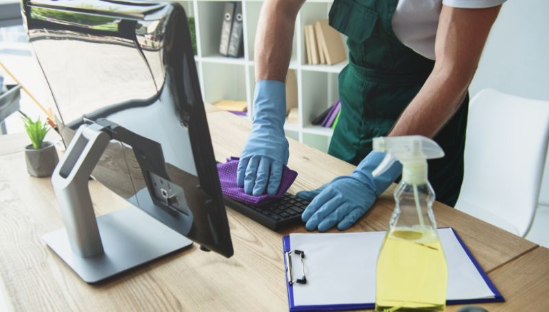 Person cleaning an office desk with a cloth