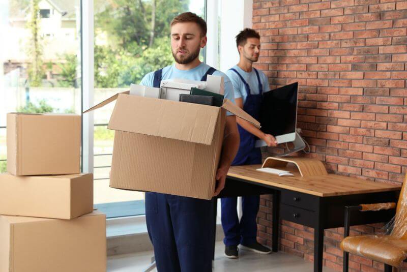 Two men moving boxes out of a property